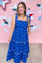 Load image into Gallery viewer, Woman wearing a blue dress with pink polka dots in front of a colorful star-patterned wall.
