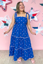 Load image into Gallery viewer, Woman in a blue dress with pink polka dots standing in front of a colorful quilted wall.
