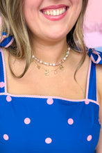 Load image into Gallery viewer, Person wearing a blue dress with pink polka dots and a pink beaded pearl necklace.
