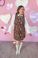 Load image into Gallery viewer, Woman in a floral dress with a white blouse against a pink wall with heart decorations
