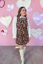 Load image into Gallery viewer, Woman in a floral dress and white boots standing in front of a pink wall with heart-shaped decorations.
