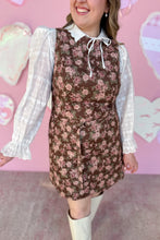 Load image into Gallery viewer, Person wearing a floral dress with a white blouse against a pink heart-patterned background

