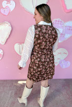 Load image into Gallery viewer, Woman wearing a floral dress and white boots in front of a pink wall with heart shapes.
