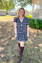 Load image into Gallery viewer, Girl wearing a brown and blue plaid skort and front tie top set with brown boots standing in front of a gazebo. 

