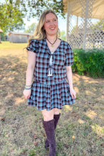 Load image into Gallery viewer, Girl wearing a brown and blue plaid skort and front tie top set with brown boots standing in front of a gazebo. 
