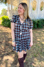 Load image into Gallery viewer, Girl wearing a brown and blue plaid skort and front tie top set with brown boots standing in front of a gazebo. 
