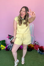 Load image into Gallery viewer, Girl wearing a yellow set with matching shorts and short sleeve top with a pink backdrop. 
