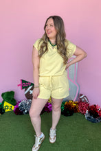 Load image into Gallery viewer, Girl wearing a yellow set with matching shorts and short sleeve top with a pink backdrop. 

