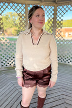 Load image into Gallery viewer, Girl wearing a cream collared sweater, brown lace satin shorts, and brown knee high boots while standing in a gazebo.
