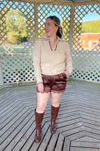 Load image into Gallery viewer, Girl wearing a cream collared sweater, brown lace satin shorts, and brown knee high boots while standing in a gazebo.
