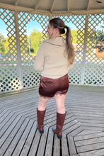 Load image into Gallery viewer, Girl wearing a cream collared sweater, brown lace satin shorts, and brown knee high boots while standing in a gazebo.
