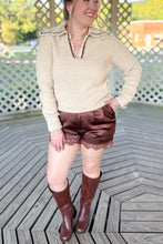 Load image into Gallery viewer, Girl wearing a cream collared sweater, brown lace satin shorts, and brown knee high boots while standing in a gazebo.
