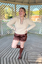 Load image into Gallery viewer, Girl wearing a cream collared sweater, brown lace satin shorts, and brown knee high boots while standing in a gazebo.
