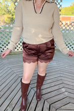 Load image into Gallery viewer, Girl wearing a cream collared sweater, brown lace satin shorts, and brown knee high boots while standing in a gazebo.
