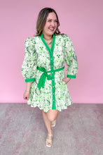 Load image into Gallery viewer, Woman wearing a green and white patterned dress with a matching belt against a pink background
