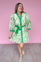 Load image into Gallery viewer, Woman wearing a green and white patterned dress with a belt against a pink background
