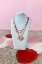 Load image into Gallery viewer, Necklace with heart pendant on a white stand against a pink background
