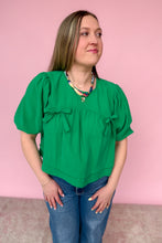 Load image into Gallery viewer, Woman wearing a green blouse with puff sleeves against a pink background
