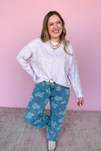 Load image into Gallery viewer, Woman wearing a light purple sweater and blue patterned pants against a pink background
