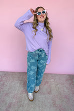 Load image into Gallery viewer, Woman wearing a light purple Mockneck and blue floral pants against a pink background
