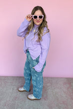 Load image into Gallery viewer, Woman wearing a lavender sweater and blue patterned pants against a pink background
