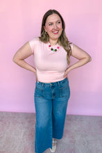 Load image into Gallery viewer, Girl wearing a pink cap sleeve top and denim jeans, standing in front of a pink backdrop.
