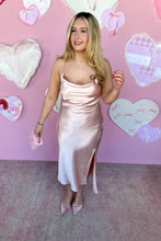 Load image into Gallery viewer, Woman in a pink satin dress standing against a pink wall with heart decorations.
