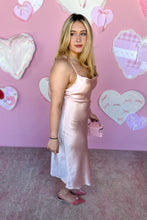Load image into Gallery viewer, Woman in a pink satin dress standing in front of a pink wall with heart decorations side view
