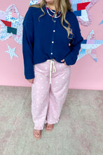Load image into Gallery viewer, Person wearing a blue cardigan and pink polka dot pants standing in front of a colorful quilt on a pink wall.
