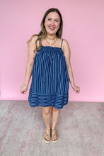 Load image into Gallery viewer, Girl in blue stripe spaghetti strap mini dress with pockets standing in front of a pink wall. 
