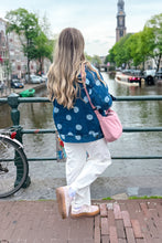 Load image into Gallery viewer, Girl standing in front of a canal wearing a denim polka dot jacket with pink bow top and white barrel jeans
