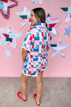 Load image into Gallery viewer, Woman wearing a colorful patchwork dress standing in front of a pink wall with star decorations.
