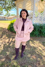 Load image into Gallery viewer, Girl wearing a faux pink leather jacket and skort set with brown undershirt and brown knee high boots standing in front of a gazebo. 
