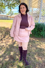 Load image into Gallery viewer, Girl wearing a faux pink leather jacket and skort set with brown undershirt and brown knee high boots standing in front of a gazebo. 
