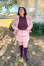 Load image into Gallery viewer, Girl wearing a faux pink leather jacket and skort set with brown undershirt and brown knee high boots standing in front of a gazebo. 
