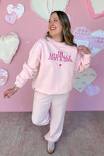 Load image into Gallery viewer, Girl in a pink sweatshirt that says I’m Literally Just a Girl and pink knit pants standing in front of a pink heart wall
