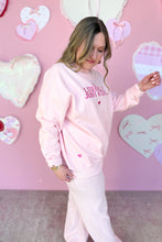 Load image into Gallery viewer, Girl in a pink sweatshirt that says I’m Literally Just a Girl and pink knit pants standing in front of a pink heart wall
