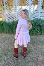 Load image into Gallery viewer, Girl wearing a pink ruffle cardigan skirt set with brown knee high boots standing in front of a gazebo. 
