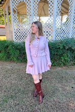 Load image into Gallery viewer, Girl wearing a pink ruffle cardigan skirt set with brown knee high boots standing in front of a gazebo. 

