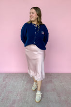 Load image into Gallery viewer, Woman wearing a blue cardigan and pink skirt against a pink wall
