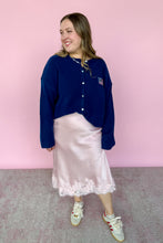 Load image into Gallery viewer, Woman wearing a blue cardigan and pink skirt against a pink background
