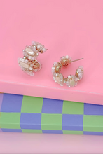 Load image into Gallery viewer, Pair of pearl hoop earrings on a pink and checkered surface
