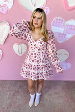 Load image into Gallery viewer, Woman wearing a pink floral dress in front of a heart-patterned wall.
