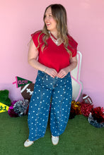 Load image into Gallery viewer, Woman wearing polkadot denim barrel jeans with a red top standing in front of a pink backdrop.
