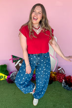 Load image into Gallery viewer, Woman wearing polkadot denim barrel jeans with a red top standing in front of a pink backdrop.
