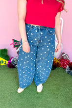 Load image into Gallery viewer, Woman wearing polkadot denim barrel jeans with a red top standing in front of a pink backdrop.
