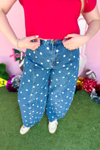 Load image into Gallery viewer, Woman wearing polkadot denim barrel jeans with a red top standing in front of a pink backdrop.
