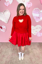 Load image into Gallery viewer, Woman wearing a red dress with a red sweater with a heart cutout design against a pink background with heart shapes.
