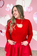 Load image into Gallery viewer, Woman wearing a red dress with a red sweater with a heart cutout design against a pink background with heart shapes.
