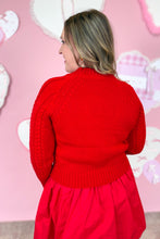 Load image into Gallery viewer, Woman wearing a red knitted sweater and skirt against a pink heart-shaped background
